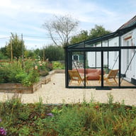 Janssens Arcadia black lean-to greenhouse in a garden