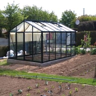 Janssens Master green greenhouse in a growing garden