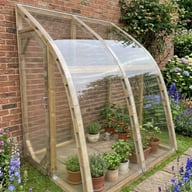 Norhage Lite Vegg 150 wooden lean-to greenhouse planted with tomatoes and herbs in a cottage garden border