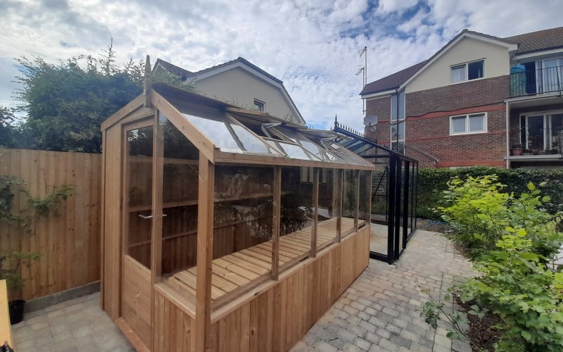 Long wooden lean-to greenhouse fitted against the rear wall of a house