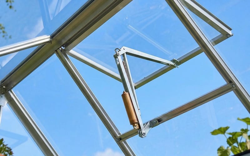 Automatic vent opener fitted to a greenhouse roof vent in a UK garden in May