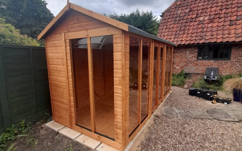 Swallow thermowood wooden greenhouse with a solid apex roof on a gravel base